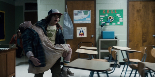 Wide shot frame from Stranger Things — standing, room, table