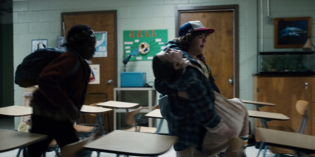 Wide shot frame from Stranger Things — sitting, standing, room