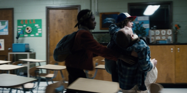 Wide shot frame from Stranger Things — standing, room, table