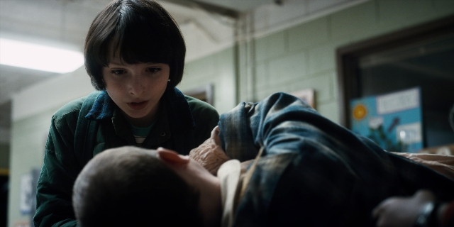 Wide shot frame from Stranger Things — standing, room, hand