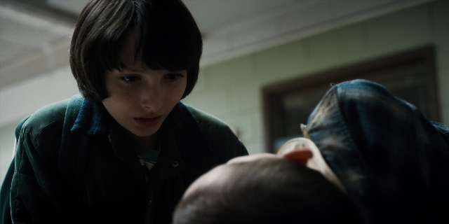 Wide shot frame from Stranger Things — room, door, face