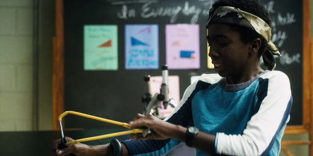 Wide shot frame from Stranger Things — shirt, face, clock