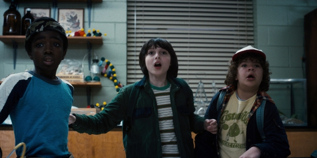 Wide shot frame from Stranger Things — standing, hat, kitchen