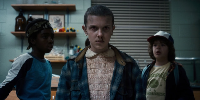 Wide shot frame from Stranger Things — standing, hat, kitchen