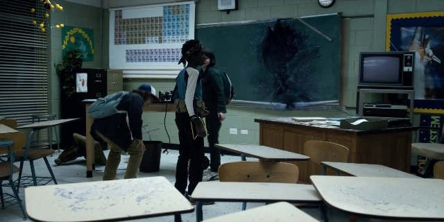 Wide shot frame from Stranger Things — desk, standing, room