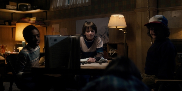 Wide shot frame from Stranger Things — sitting, standing, room