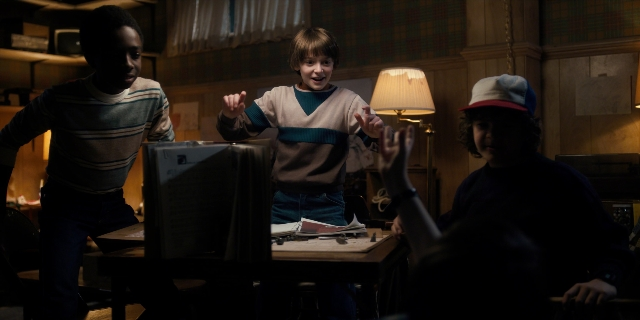Wide shot frame from Stranger Things — sitting, standing, room