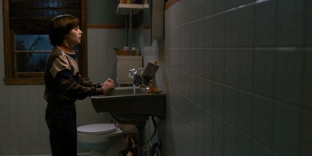 Wide shot frame from Stranger Things — standing, bathroom, toilet