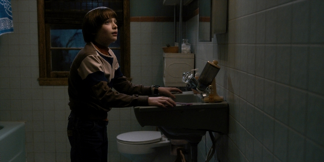 Wide shot frame from Stranger Things — standing, mirror, bathroom