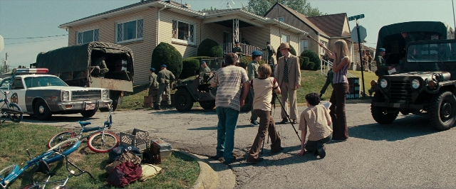 Wide shot frame from Super 8 — standing, dialogue, street