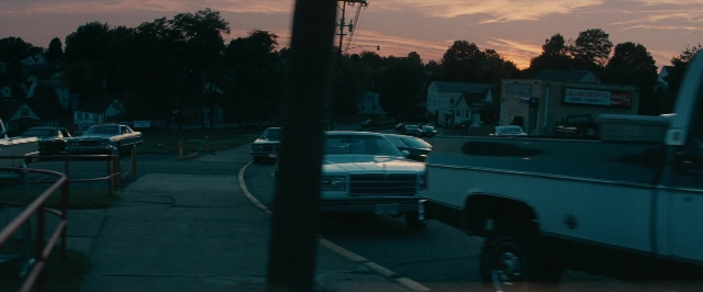 Wide shot frame from Super 8 — bed, street, car