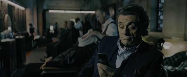 Medium shot frame from John Wick: Chapter 3 - Parabellum — sitting, phone, suit