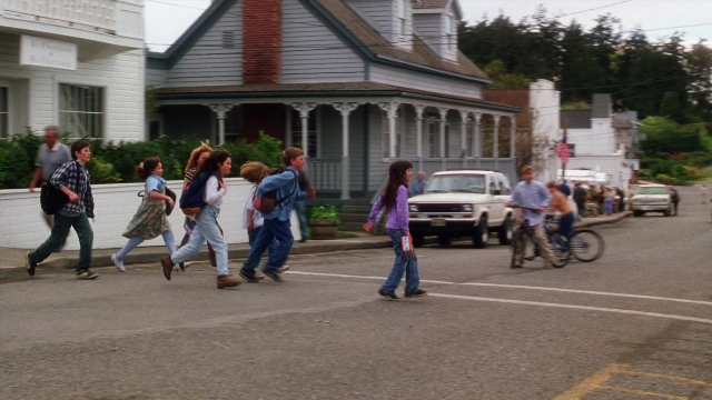 Wide shot frame from Practical Magic — walking, street, car