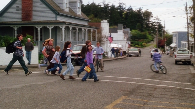Wide shot frame from Practical Magic — walking, street, house