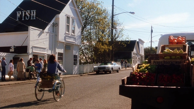 Wide shot frame from Practical Magic — walking, street, car