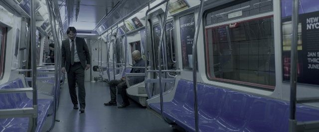 Wide shot frame from John Wick: Chapter Two — sitting, walking, suit