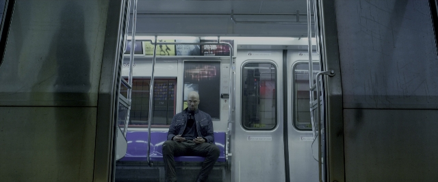 Wide shot frame from John Wick: Chapter Two — sitting, phone, door