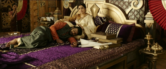 Medium shot frame from Bãhubali 2: The Conclusion — sitting, book, bed