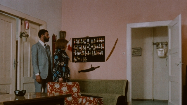 Wide shot frame from Angst essen Seele auf — desk, standing, suit