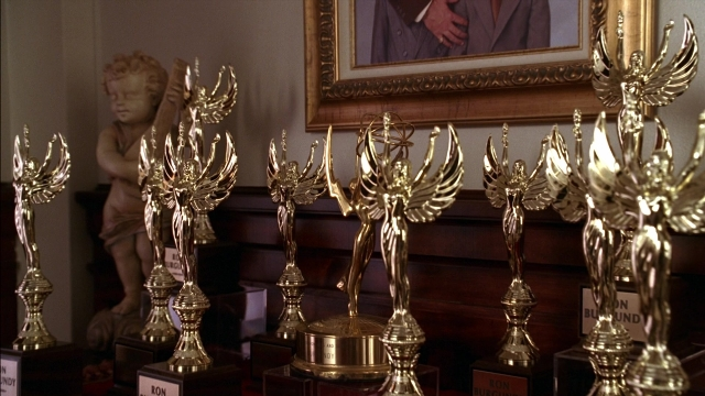 Wide shot frame from Anchorman: The Legend of Ron Burgundy — table, suit, tie