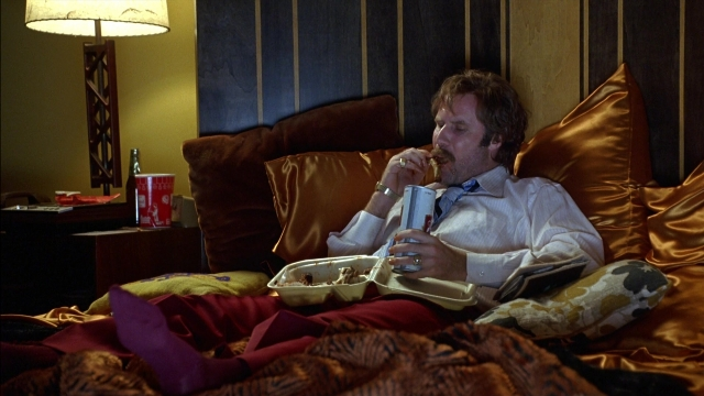 Frame from Anchorman: The Legend of Ron Burgundy — sitting, book, bed