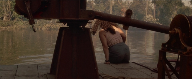 Wide shot frame from Anaconda — sitting, water, face