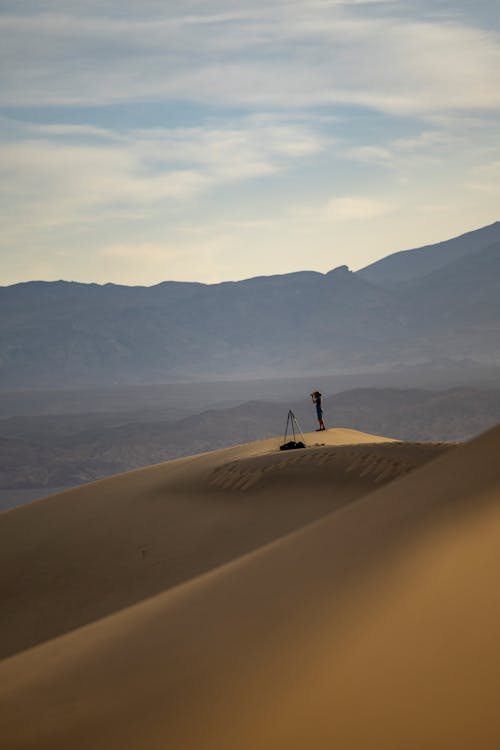 Traveler standing atop dune overlooking desert