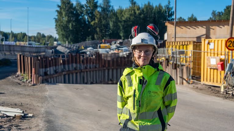 En kvinna med glasögon och byggarbetskläder.