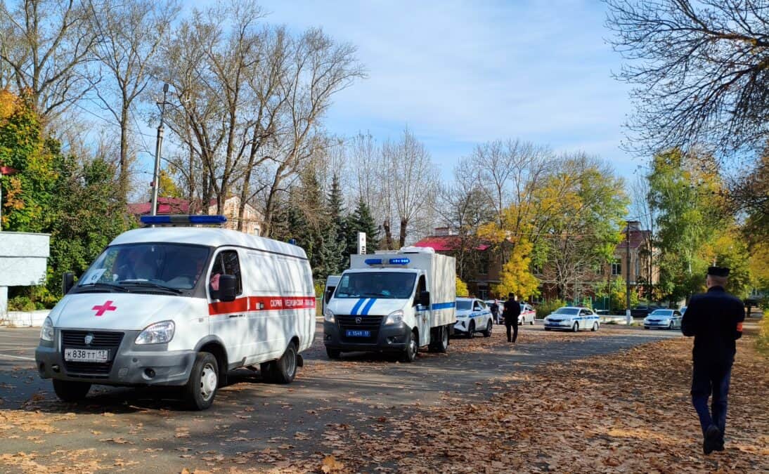 Два автомобиля экстренных служб стоят на улице среди осенних деревьев.