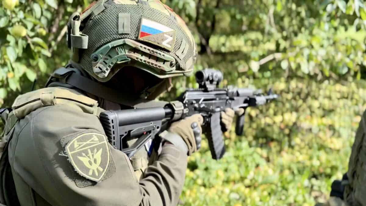 Боец в шлеме и защитной экипировке целится из автомата.