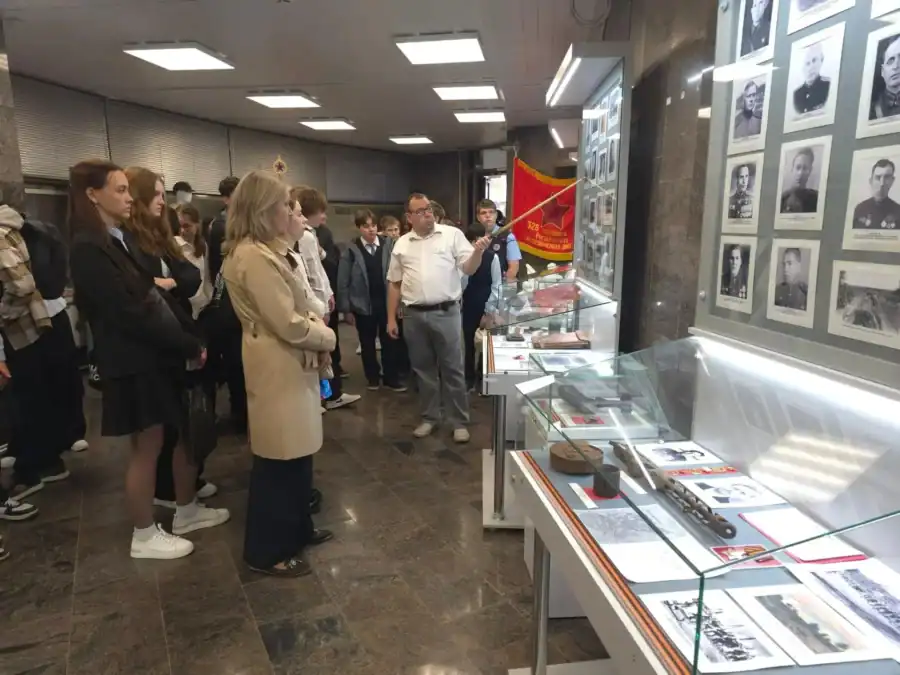 Школьники рассматривают документы и фотографии в музейной витрине.
