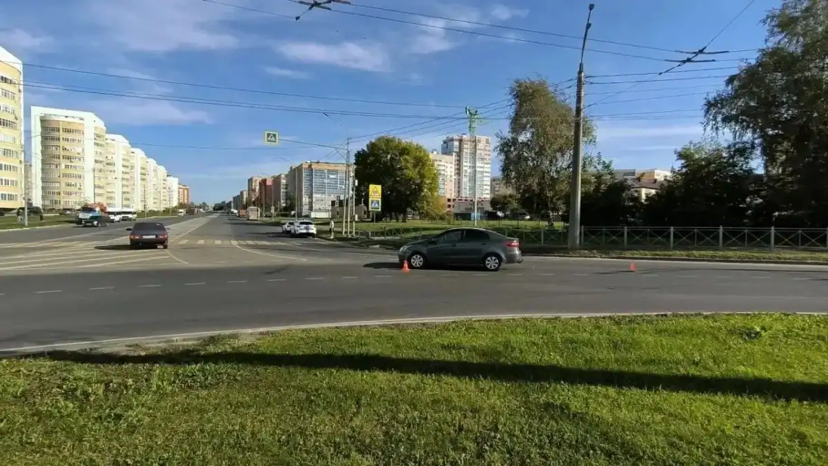 Легковой автомобиль остановлен на широкой городской дороге между дорожными конусами.