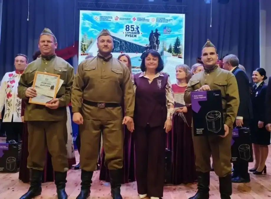 Участники ансамбля с дипломом и подарочными пакетами стоят на сцене.