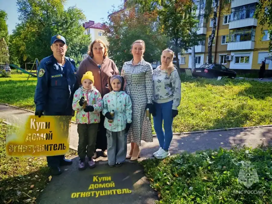 Сотрудник МЧС, женщины и дети стоят рядом с надписью о покупке дымового извещателя.