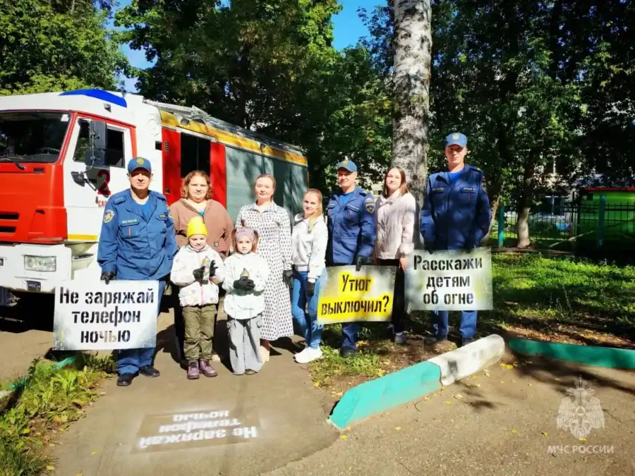 У пожарной машины участники акции держат таблички с противопожарными напоминаниями.