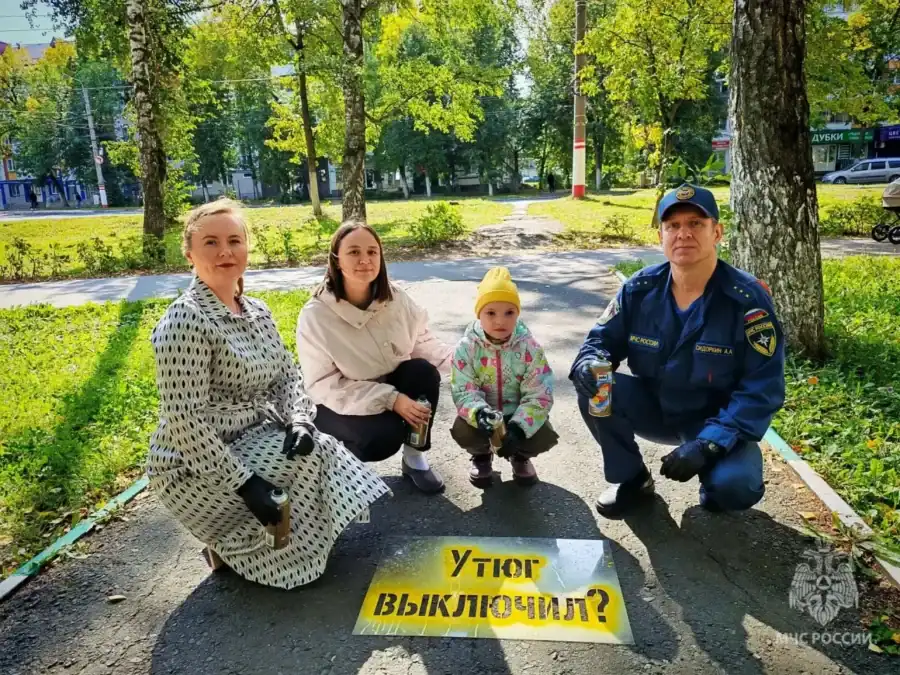 Женщины, ребёнок и сотрудник МЧС позируют рядом с надписью «Утюг выключил?».