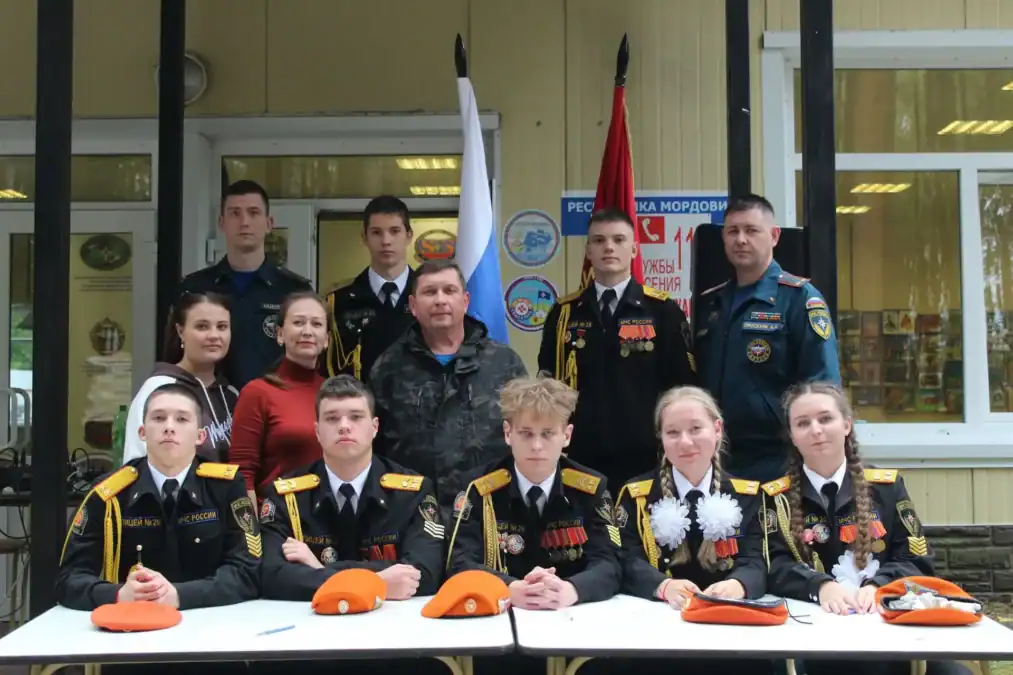 Участники соревнований в кадетской форме позируют с наставниками у входа в здание.