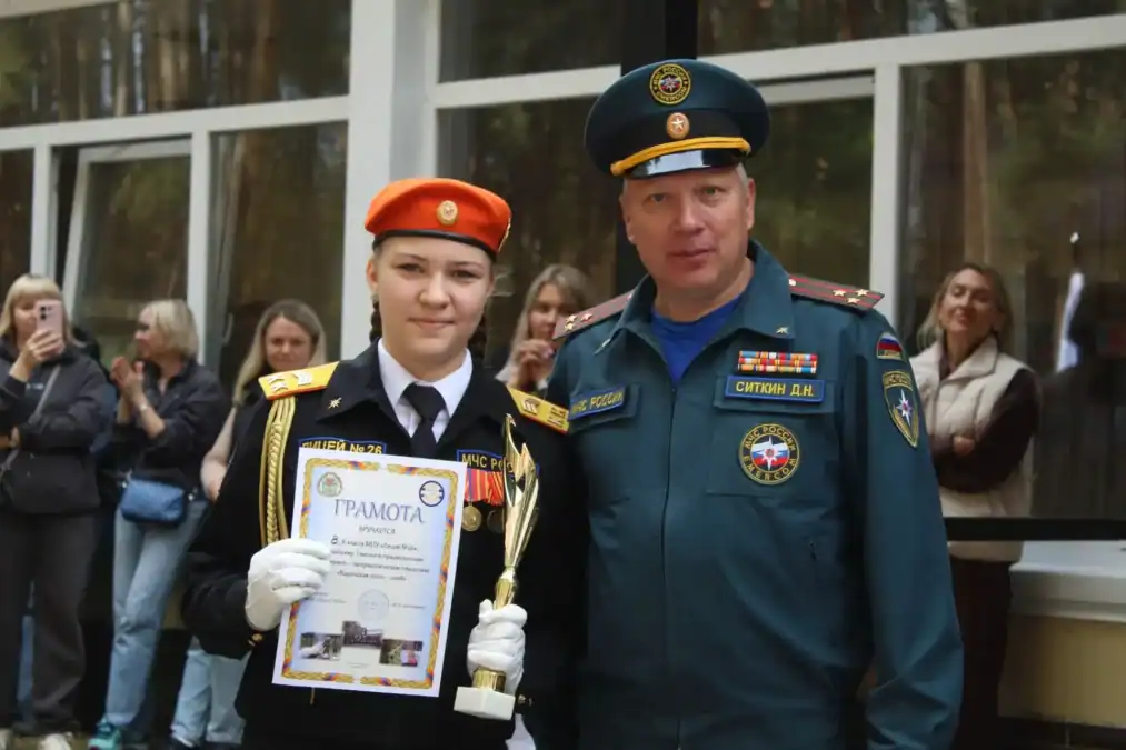Кадет в парадной форме держит грамоту и кубок рядом с сотрудником МЧС.