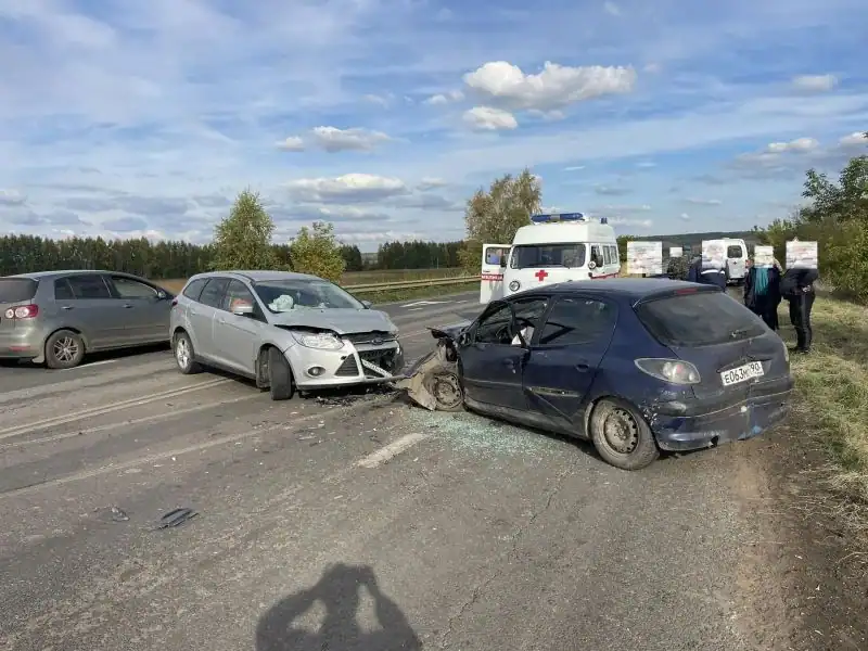 Повреждённые легковые автомобили стоят на дороге рядом с машиной скорой помощи.