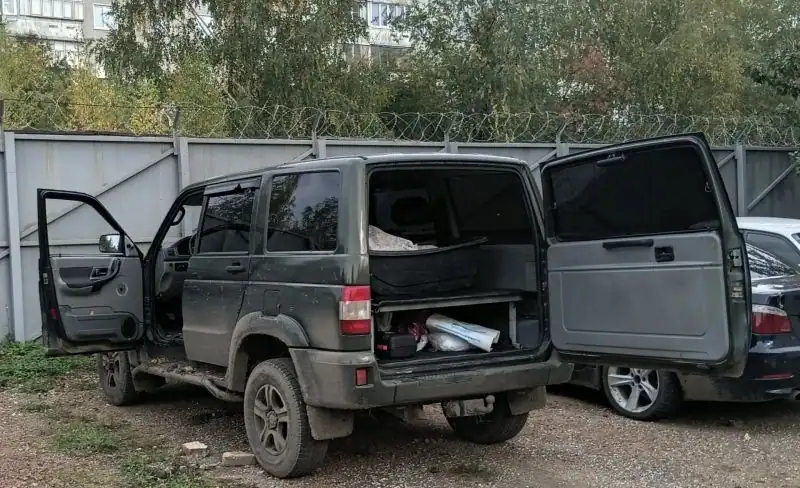 УАЗ стоит с открытыми дверями и багажником, внутри видны свёртки.