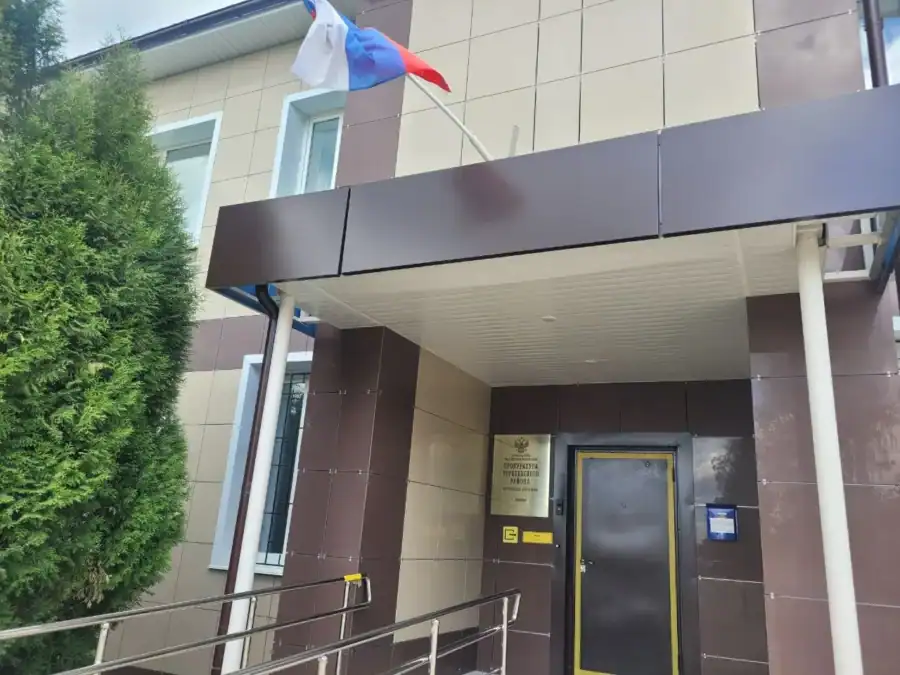 Вход в здание суда с российским флагом над козырьком.