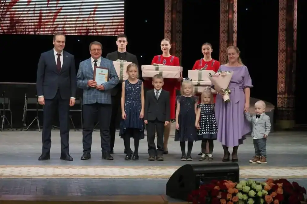 Семья с детьми получает награду и подарки на сцене.