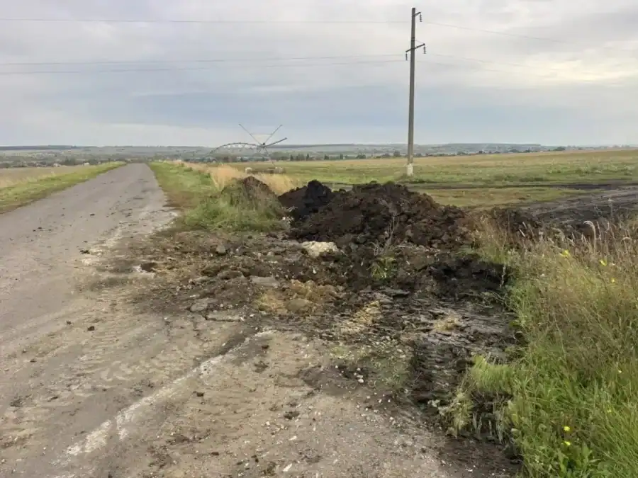 Разрытая обочина и насыпь грунта рядом с сельской дорогой.