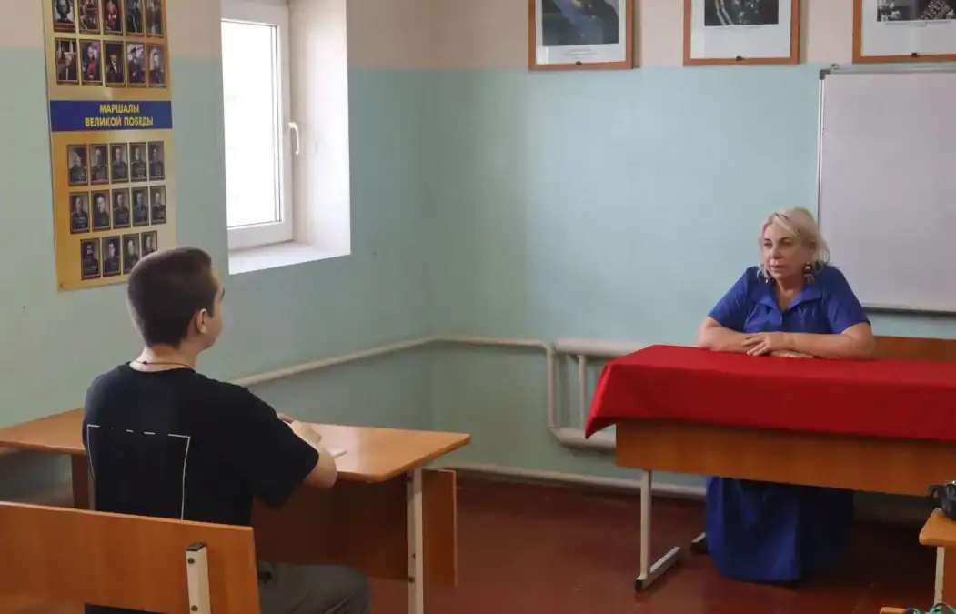 Женщина беседует с подростком за столами в учебном классе.