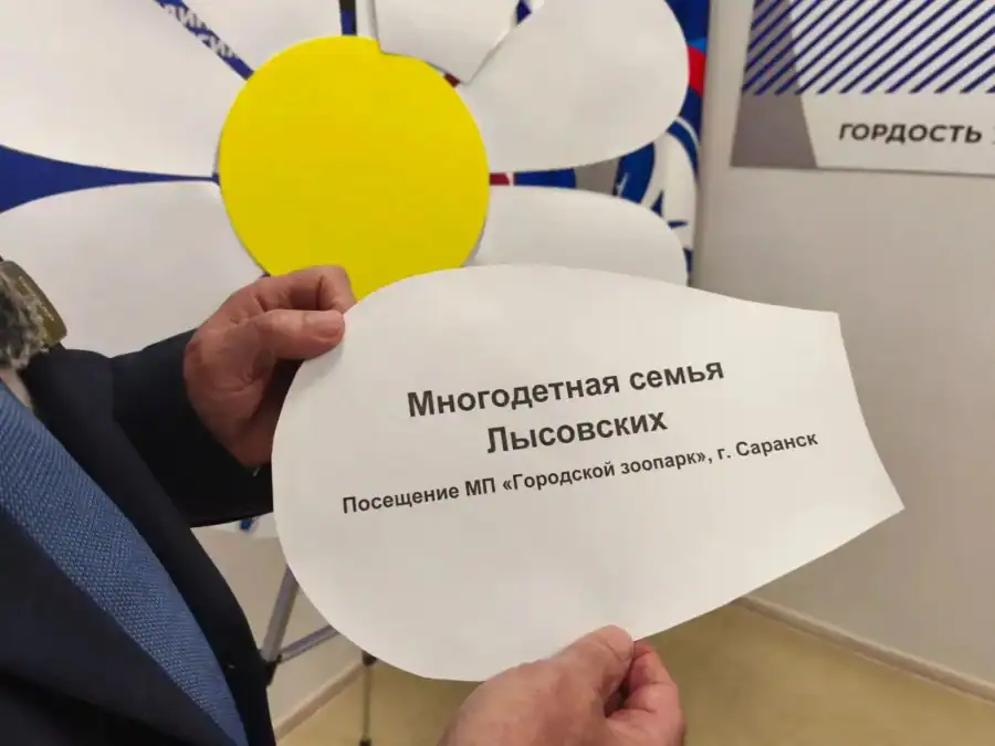 Руки держат лепесток с желанием семьи посетить городской зоопарк Саранска.