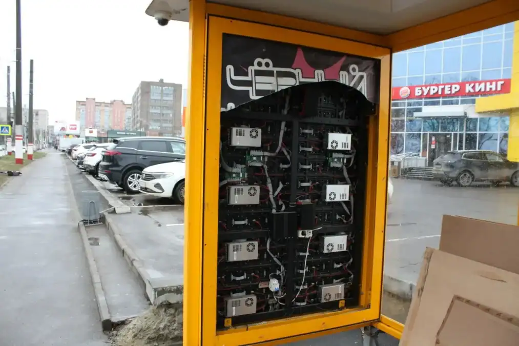 В жёлтом остановочном павильоне открыт модуль с электронными блоками и проводами.