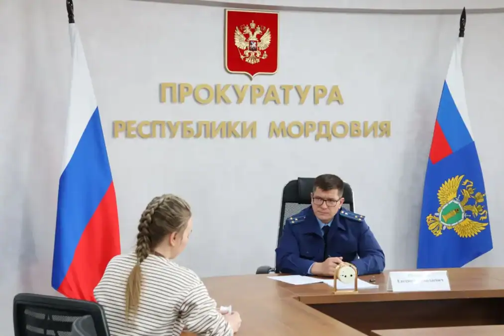 Сотрудник прокуратуры беседует с посетительницей за рабочим столом.