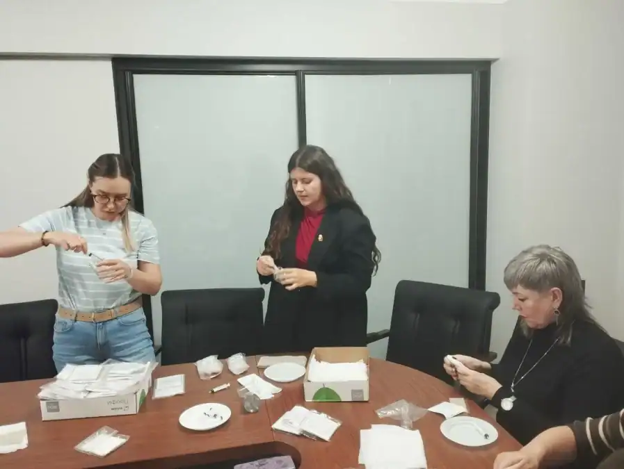 Три сотрудницы подготавливают и упаковывают комплекты рядом с коробками материалов.