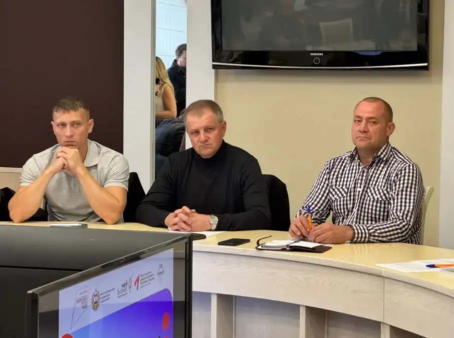 Трое участников занятия сидят за столом, перед ними включён монитор.
