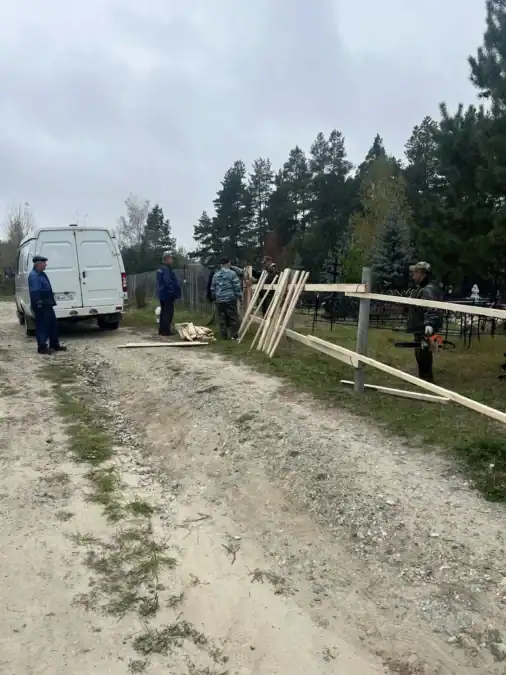 Рабочие собирают деревянное ограждение рядом с белым фургоном.